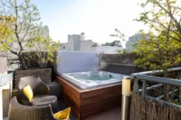 Spa privatif à Paris de MAISON LAVAUD - Paris, sur une terrasse en bois entourée de plantes et équipée de fauteuils.