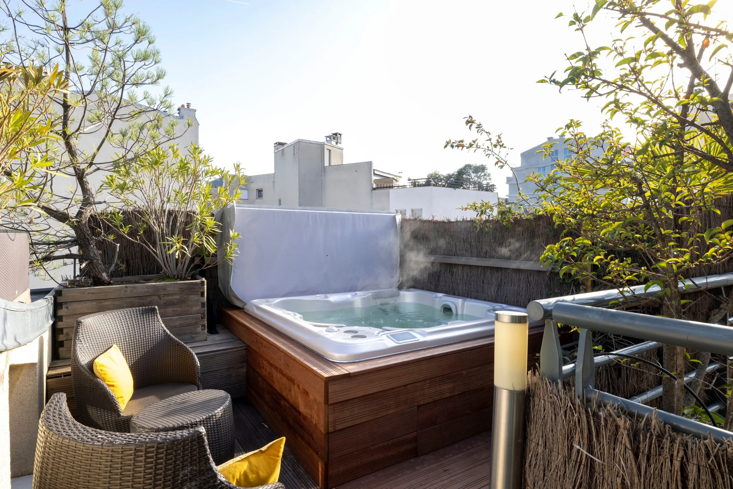 Spa privatif à Paris de MAISON LAVAUD - Paris, sur une terrasse en bois entourée de plantes et équipée de fauteuils.