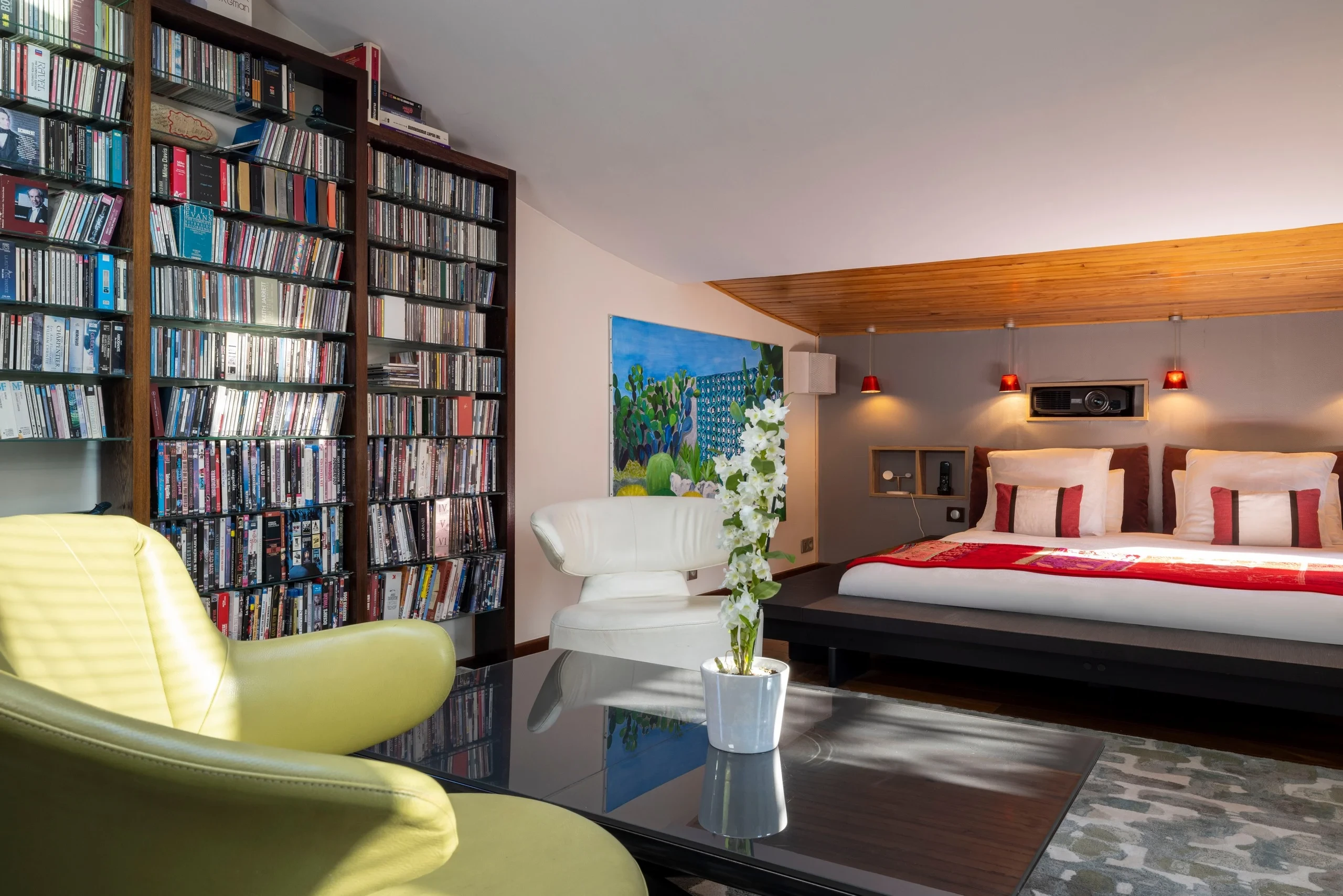 Chambre de la résidence hôtelière de luxe MAISON LAVAUD - Paris, avec lit double, fauteuils et grande collection de CD et DVD.