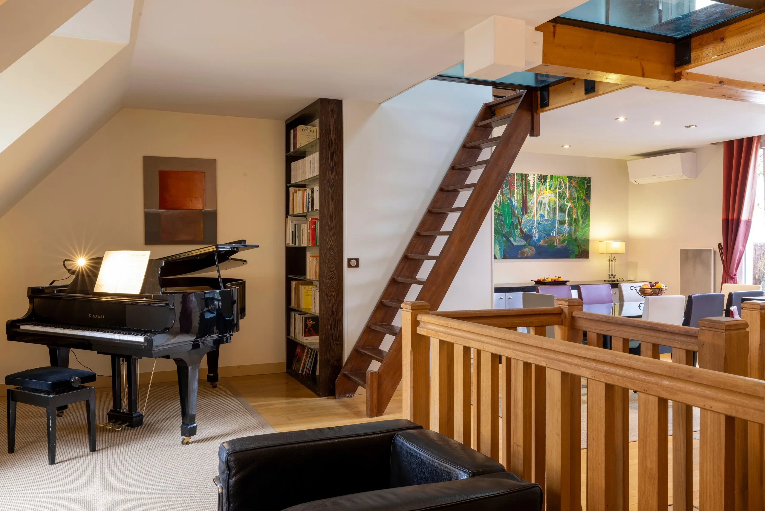 Piano à queue et escalier en bois menant à une mezzanine dans les espaces de MAISON LAVAUD - Paris, résidence hôtelière de luxe à Paris.