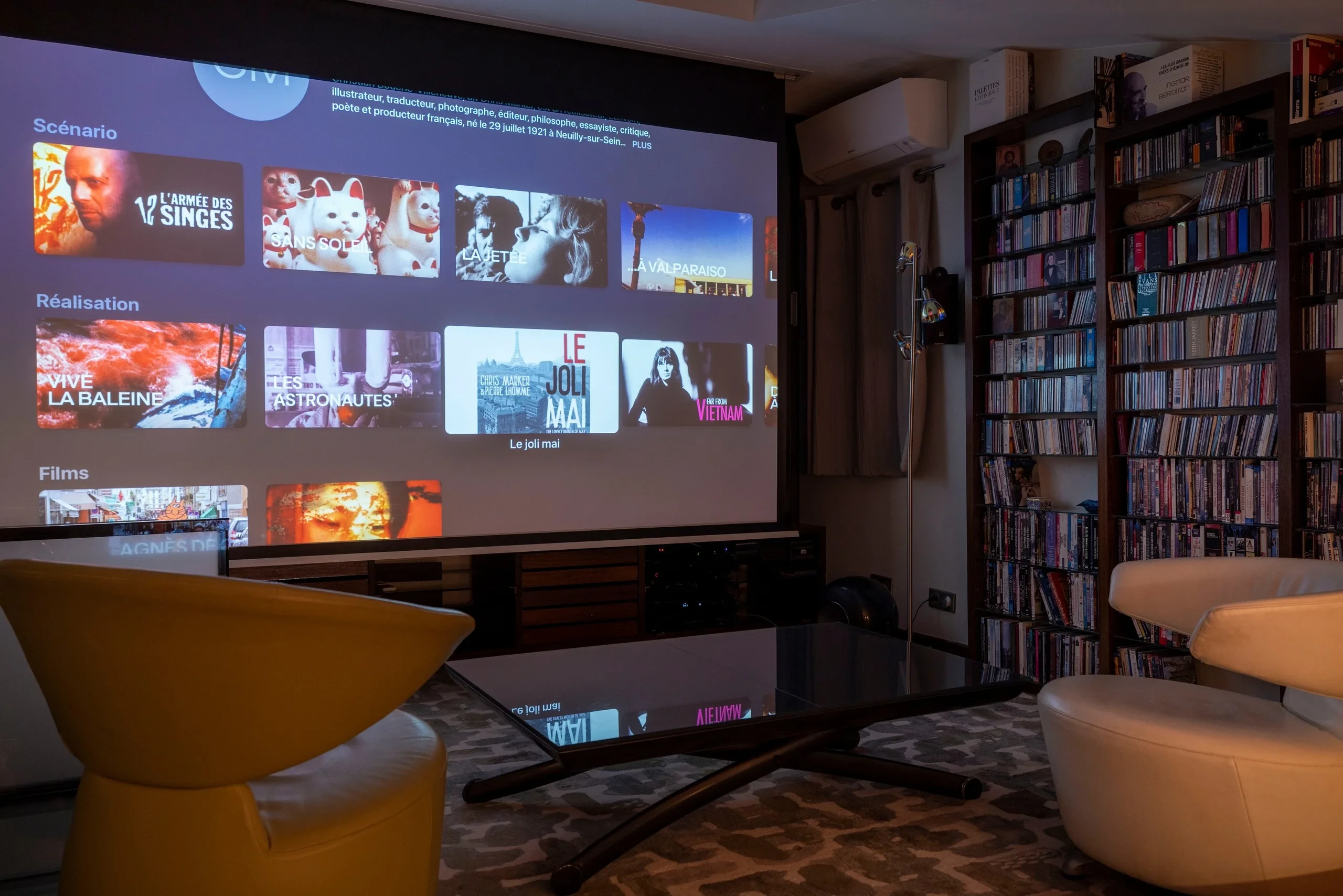 Salon de MAISON LAVAUD - Paris avec grand écran de projection, fauteuils et bibliothèque de films.