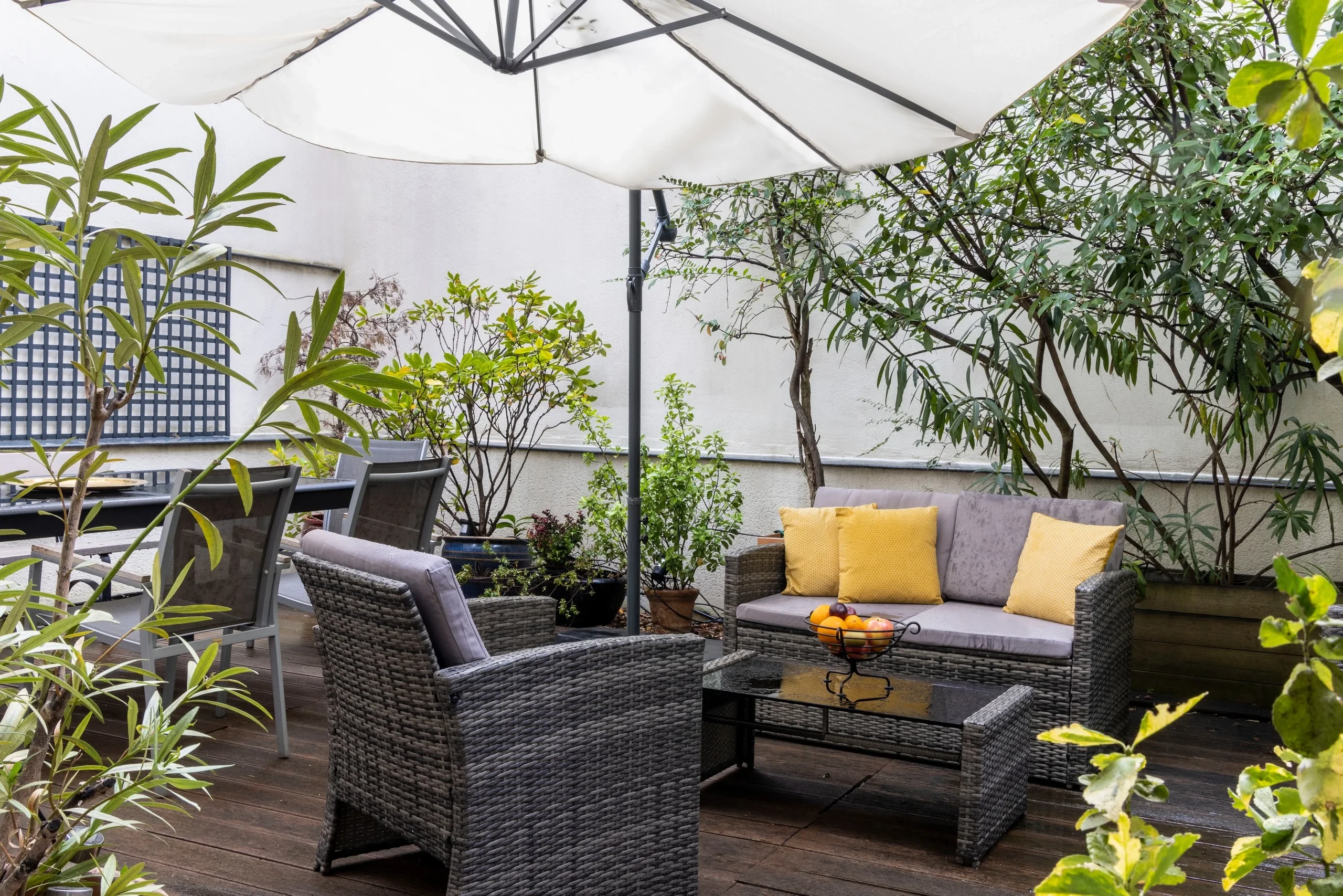 Terrasse végétalisée de MAISON LAVAUD - Paris, avec salon de jardin sous un grand parasol et espace repas.
