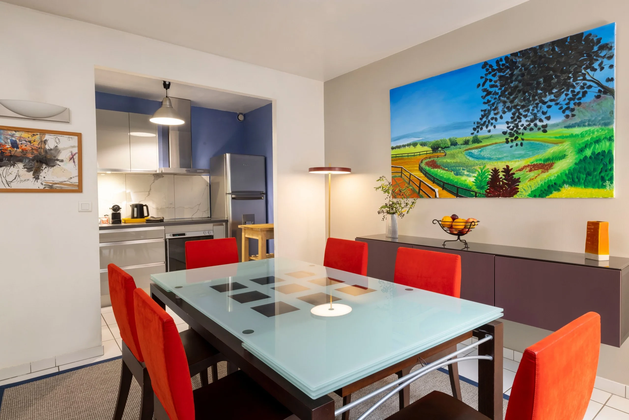 Salle à manger de MAISON LAVAUD - Paris, résidence hôtelière de luxe à Paris, avec table en verre et chaises rouges.