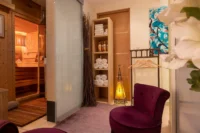 Espace de repos avec fauteuil et sauna en bois dans un spa privatif à Paris.