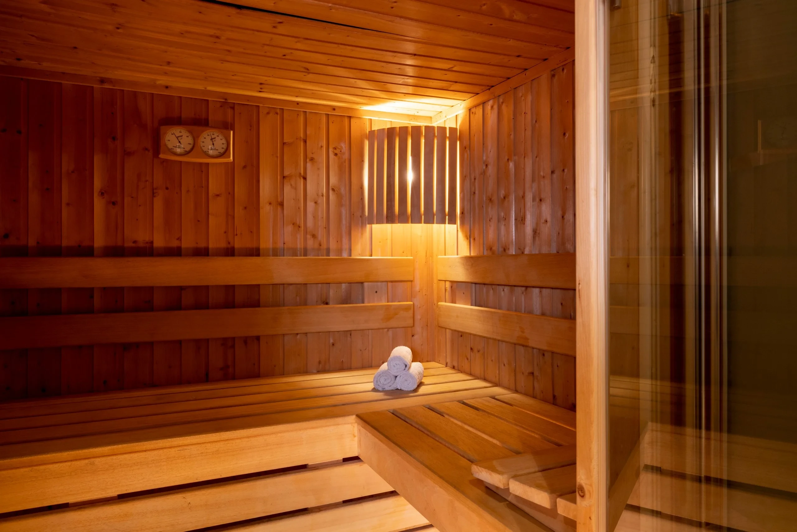 Intérieur du sauna de MAISON LAVAUD - Paris, avec banquettes en bois disposées en angle.