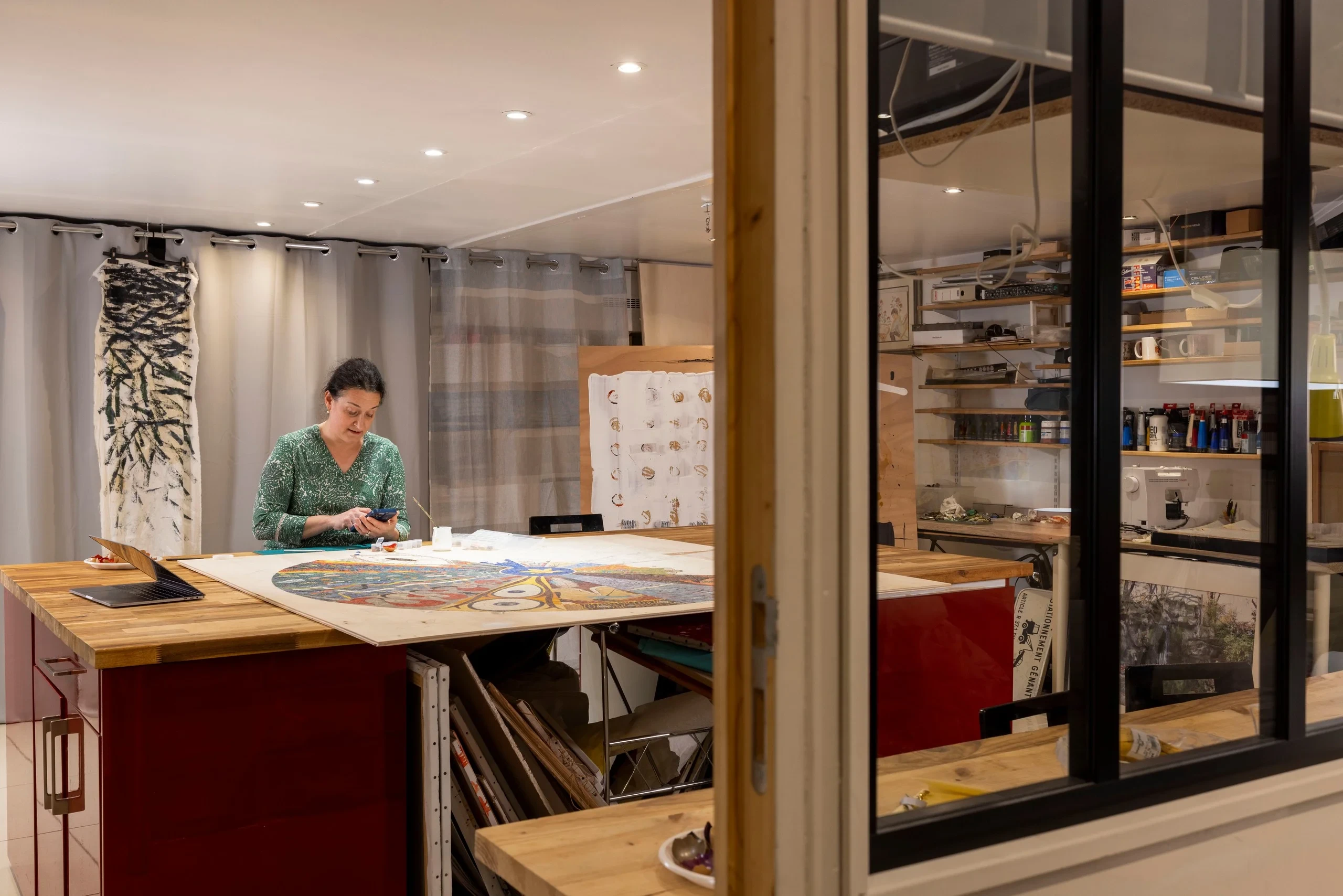Atelier de MAISON LAVAUD - Paris, hôtel d’art à Paris, où une femme consulte son téléphone devant une grande composition colorée.