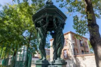 Fontaine Wallace dont les cariatides soutiennent un dôme ouvragé, sous les arbres.