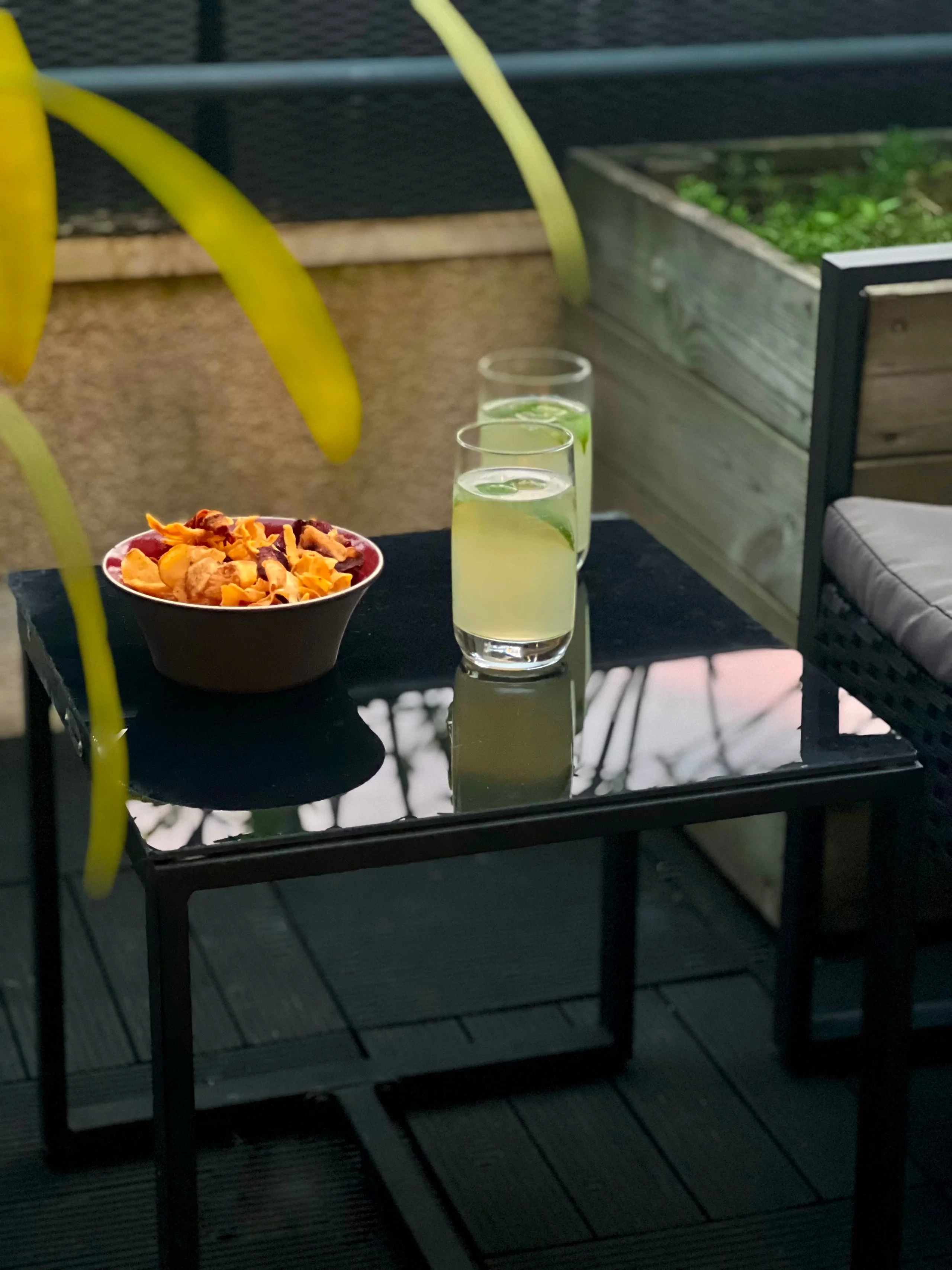 Deux verres de boisson au citron vert et un bol de chips sur une table de terrasse de MAISON LAVAUD - Paris.