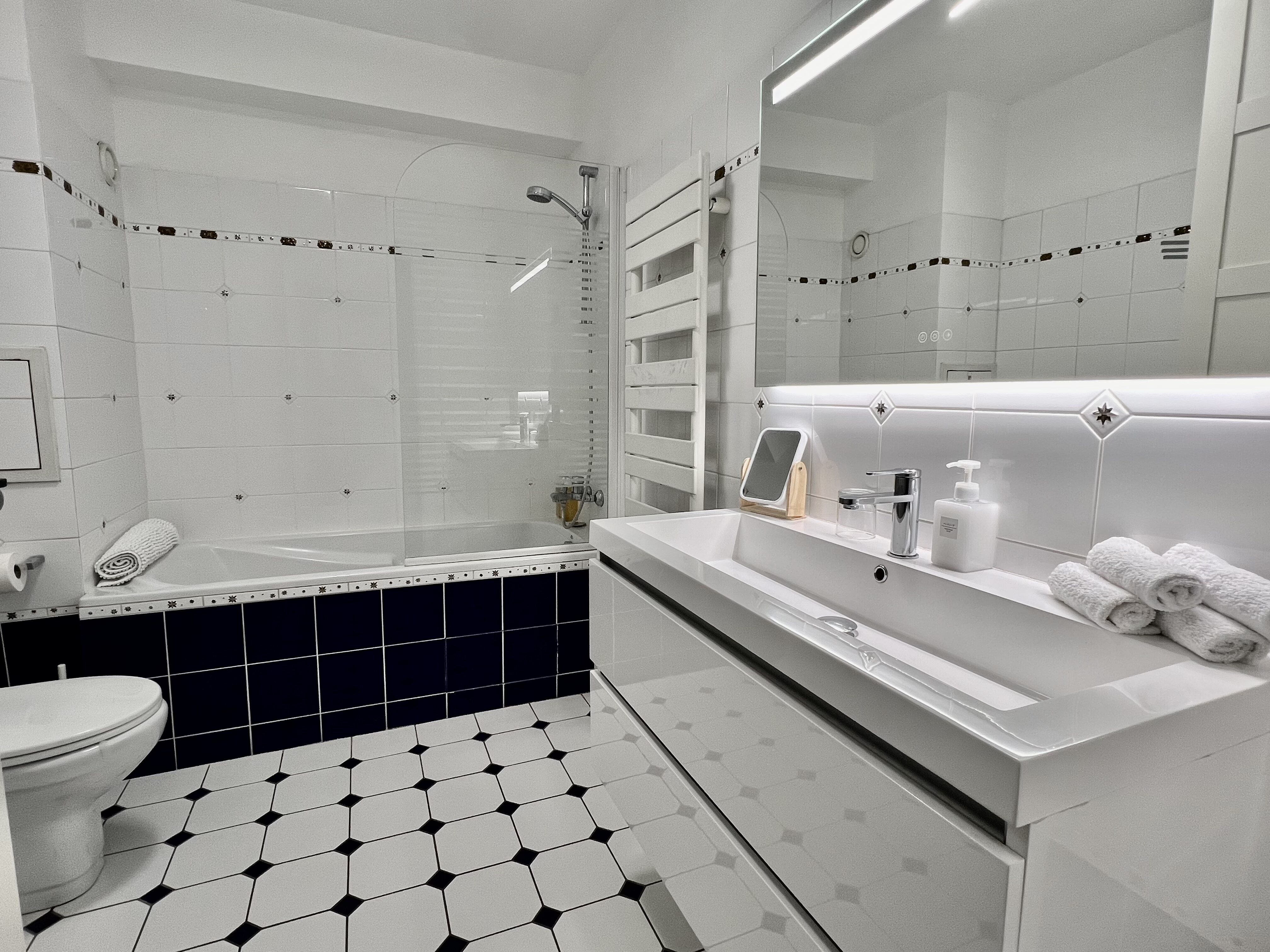 Salle de bains de MAISON LAVAUD - Paris avec baignoire à pare-douche vitré et grand lavabo rectangulaire.