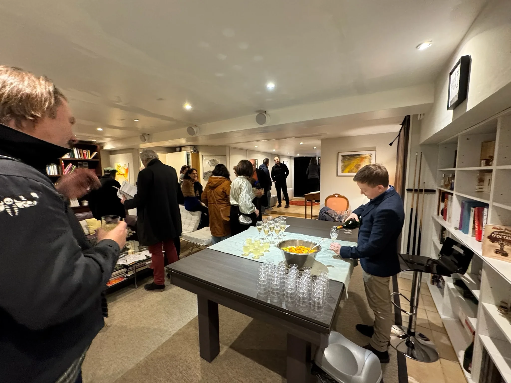 Personnes réunies dans un salon où des boissons sont servies autour d’une grande table.