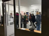 Vue depuis la vitrine sur des visiteurs réunis à MAISON LAVAUD - Paris, galerie d’art contemporain à Paris.
