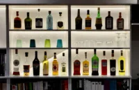 Bouteilles de spiritueux et verres disposés sur les étagères rétroéclairées du bar de MAISON LAVAUD - Paris.