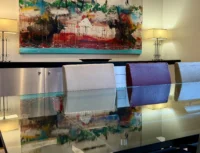 Table en verre reflétant une grande peinture abstraite multicolore dans un appart hôtel de luxe à Paris.