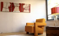 Fauteuil jaune sous un triptyque de bustes peints à MAISON LAVAUD - Paris, appart hôtel de luxe à Paris.