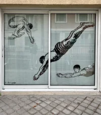 Dessins noirs de plongeurs dans différentes positions sur les deux panneaux d’une baie vitrée.