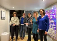 Cinq femmes posent ensemble dans la galerie, plusieurs tenant un verre à la main.