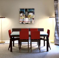 Table à manger entourée de six chaises rouges sous une peinture abstraite à MAISON LAVAUD - Paris.